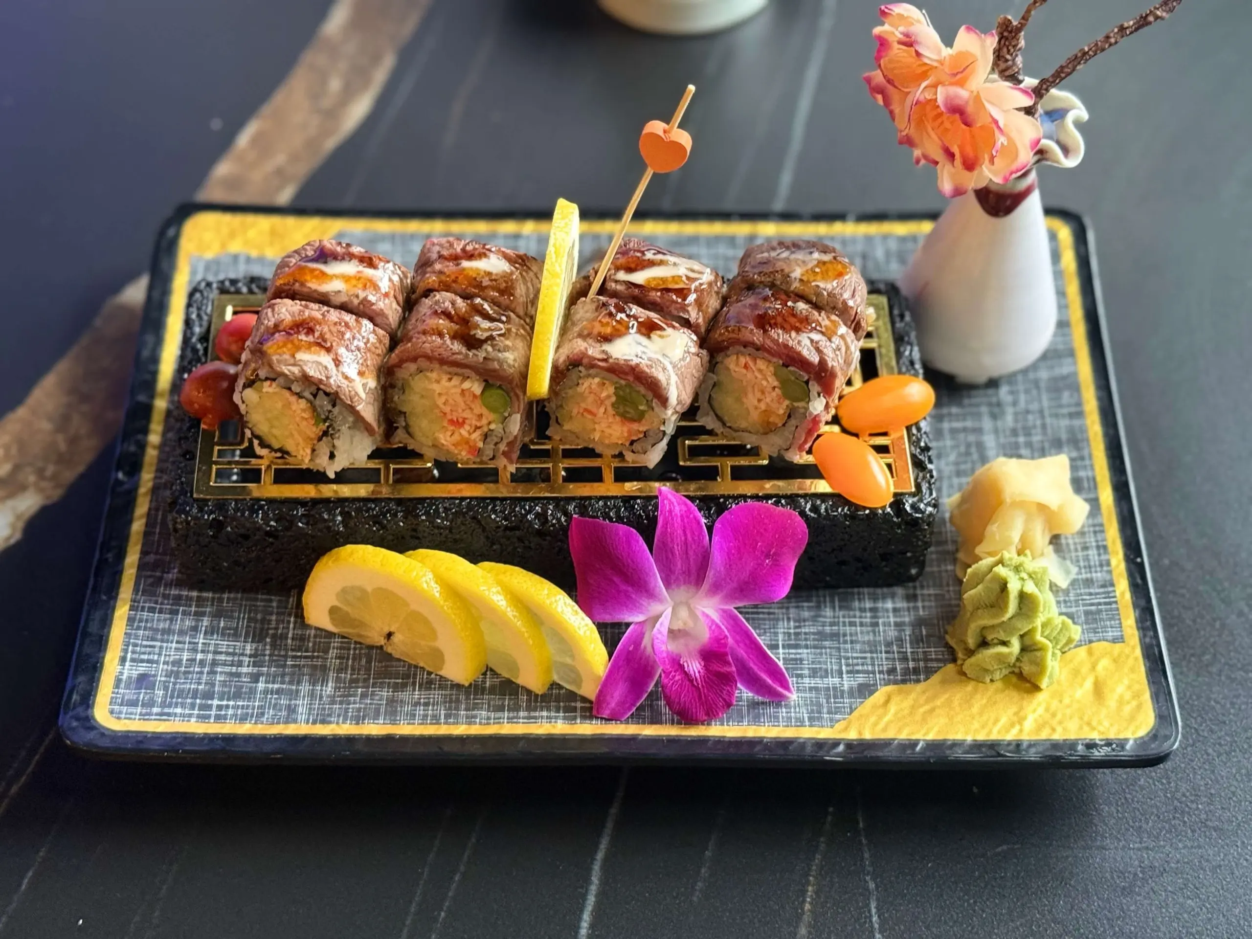 Sushi rolls wrapped with beef, filled with ingredients, served with lemon slices and wasabi
